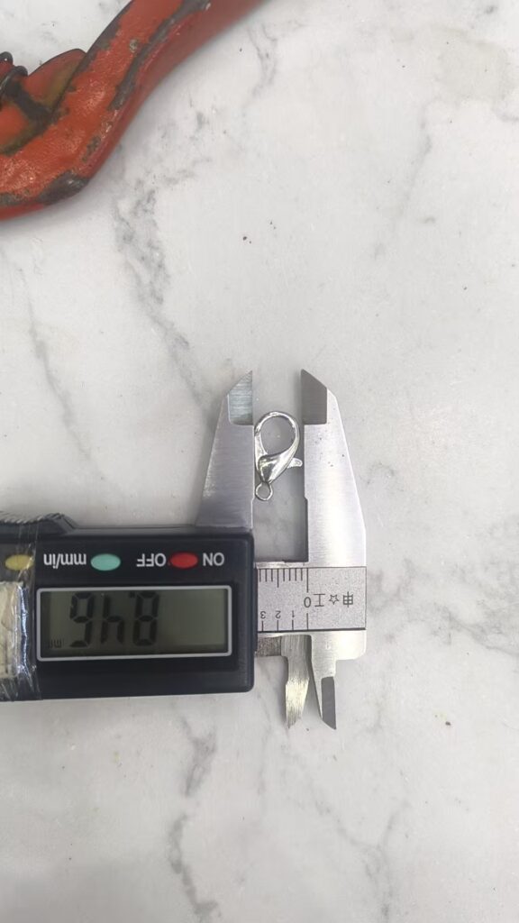 Metal chain connector being measured with a digital calliper